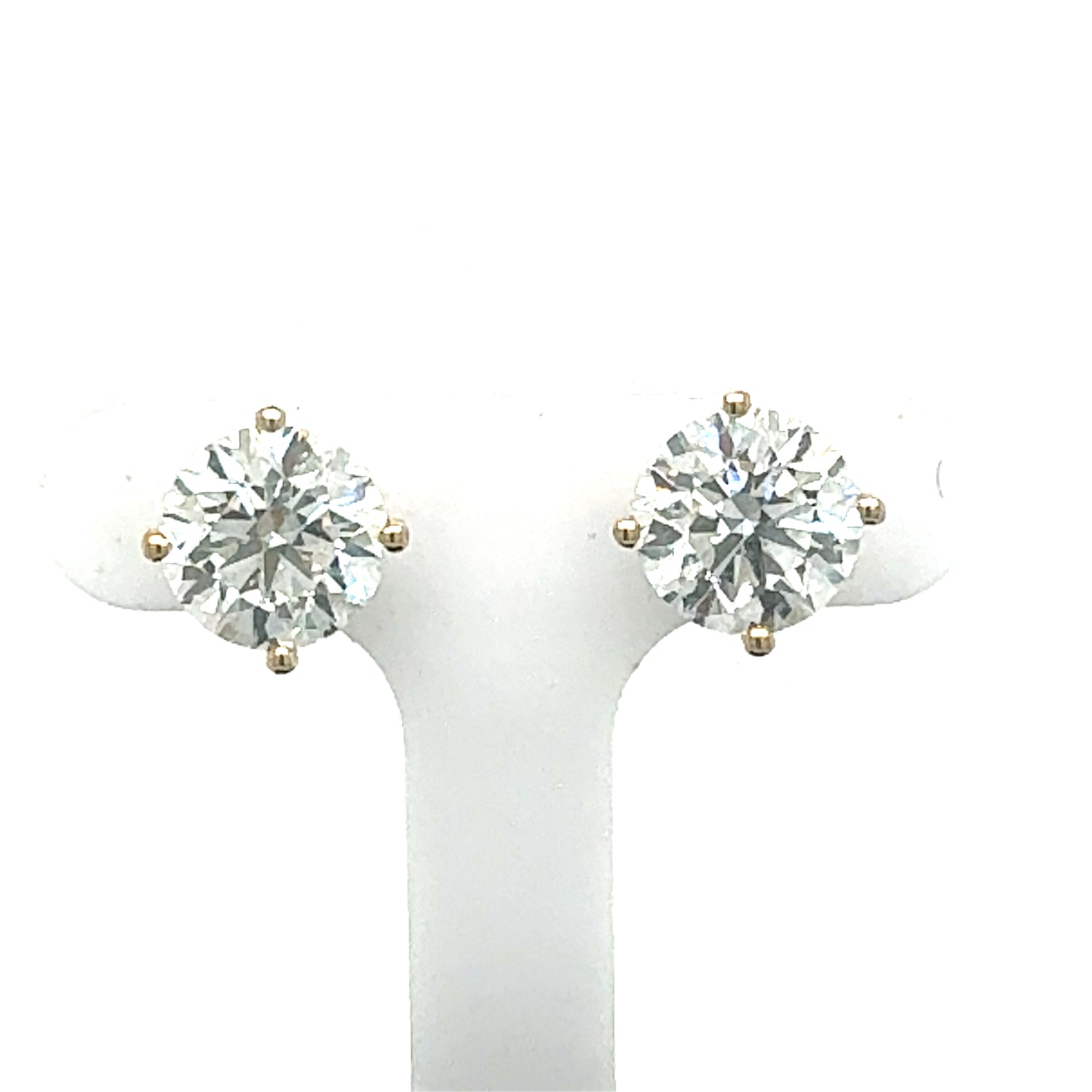 A pair of lab diamond studs set in 14Kt gold, with one earring in yellow gold and the other in white gold, displayed on a white mount.