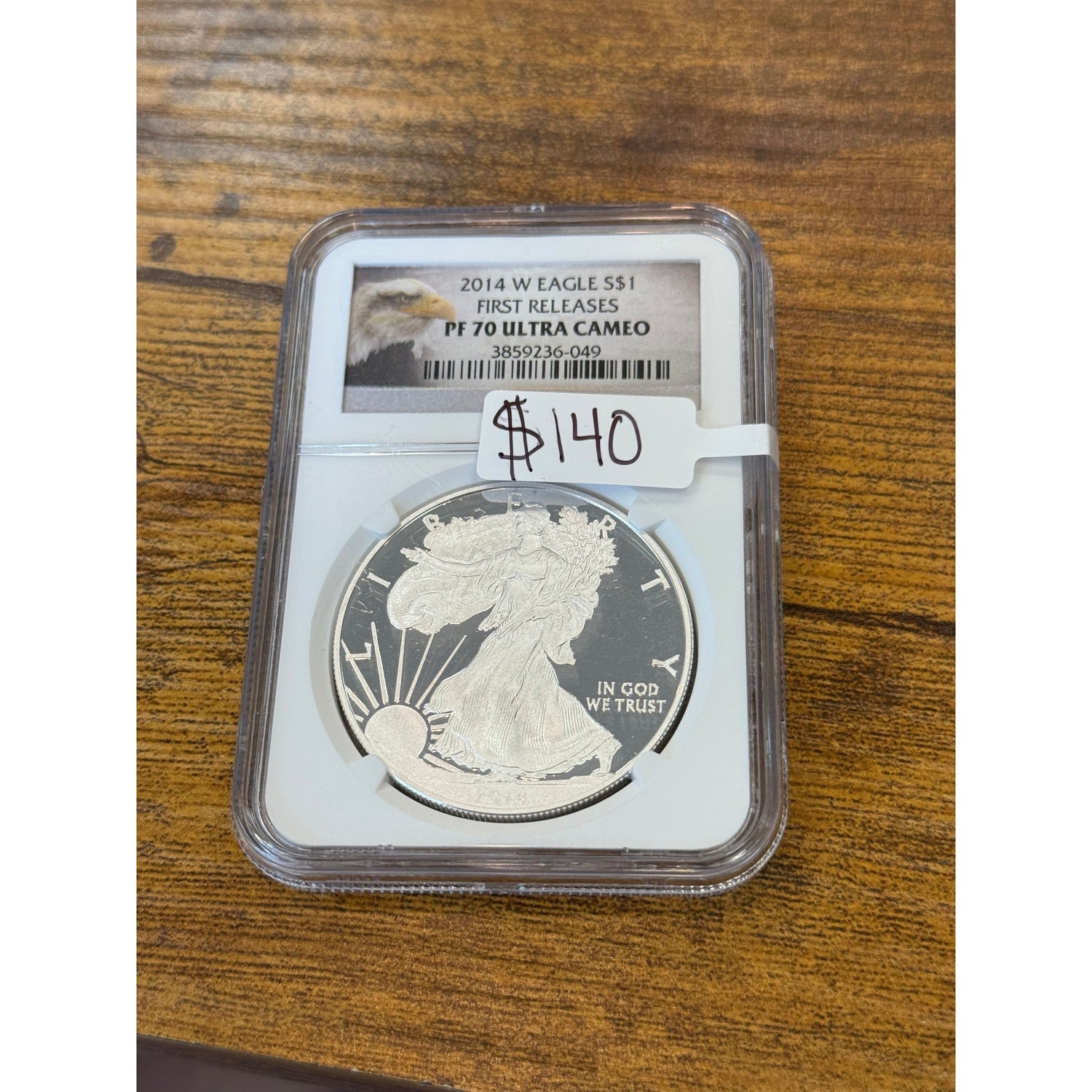 Silver coin in a protective case on a wooden surface