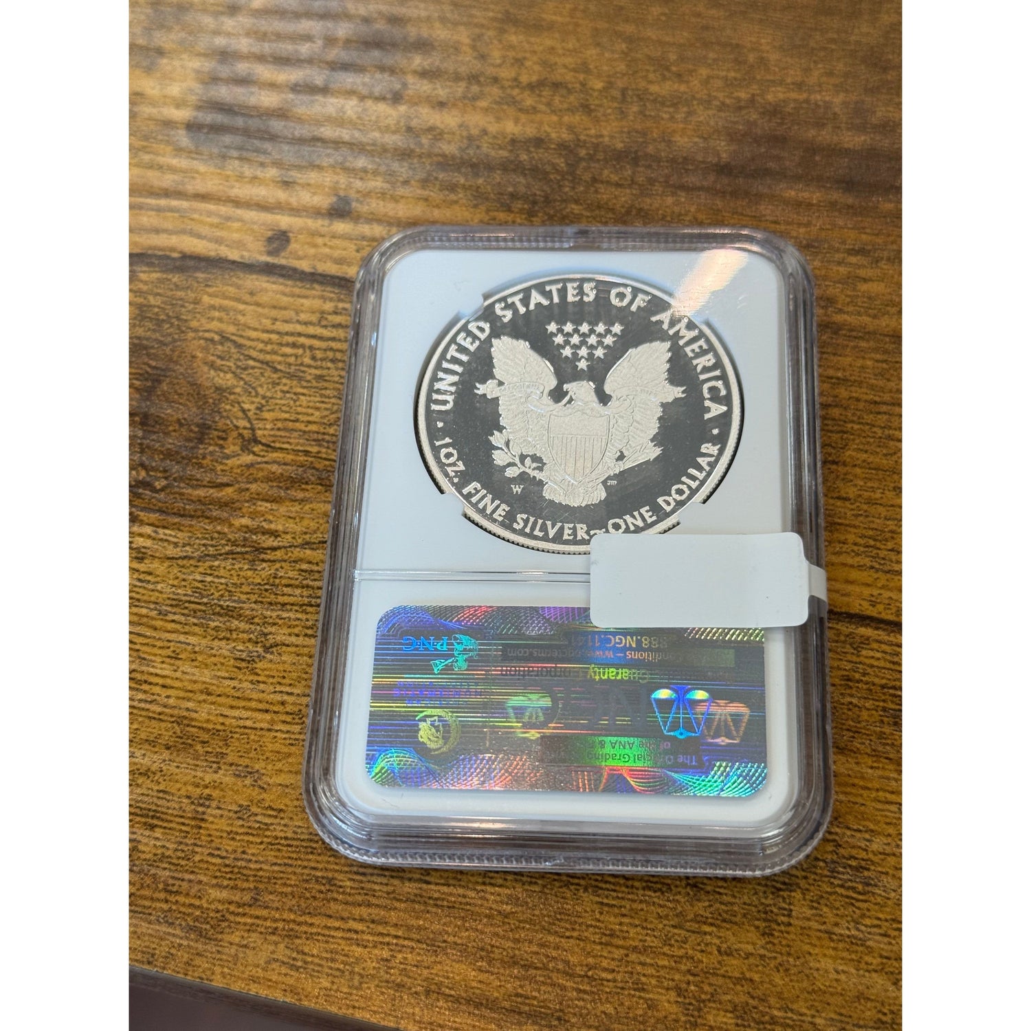 Silver coin in a protective case with a holographic label on a wooden surface