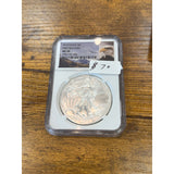 Silver eagle coin in a protective case on a wooden surface