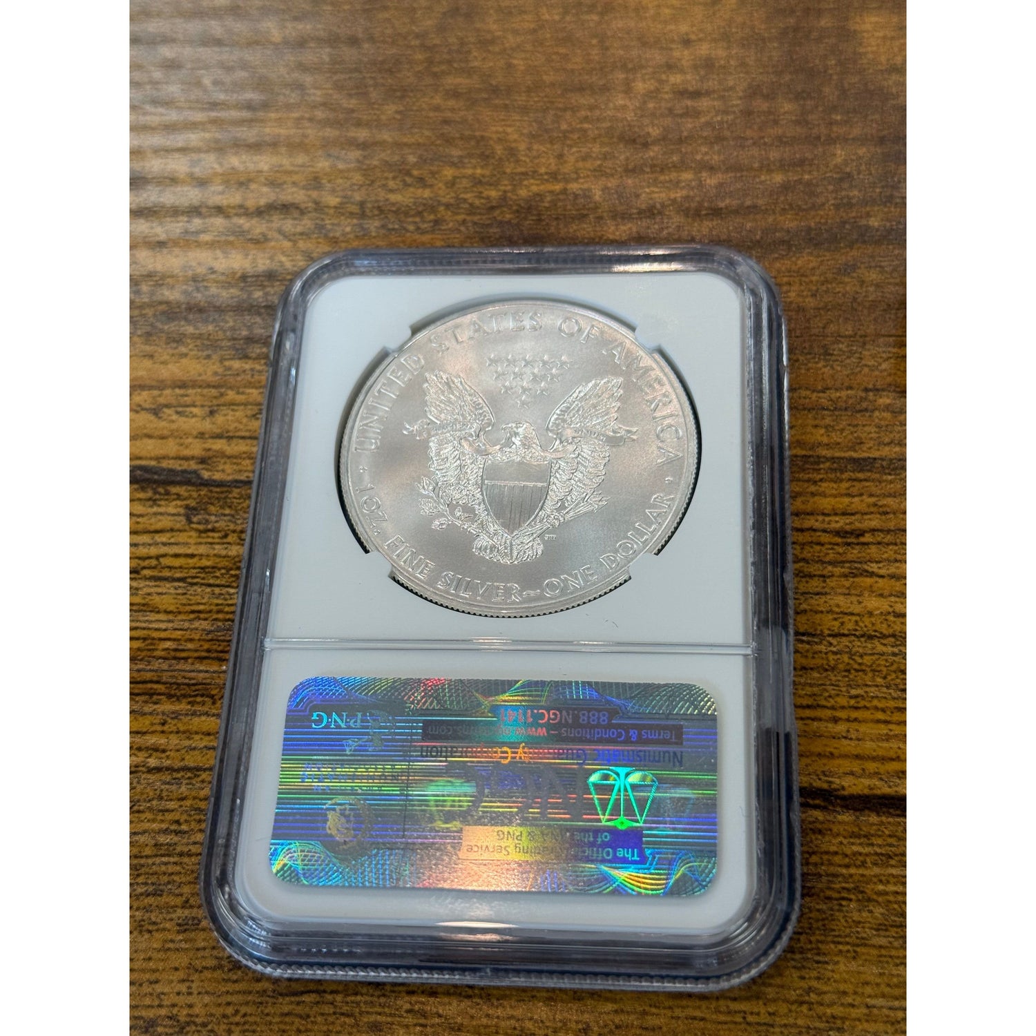 Silver coin in a protective case on a wooden surface