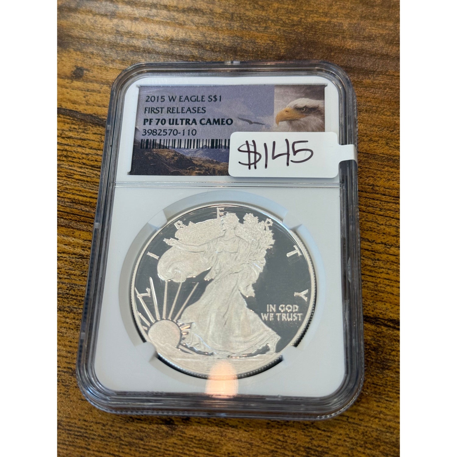 Silver eagle coin in protective case with grading information on a wooden surface
